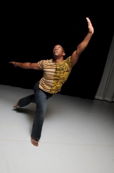 Boris Willis reaching upward in a striped shirt against a studio backdrop