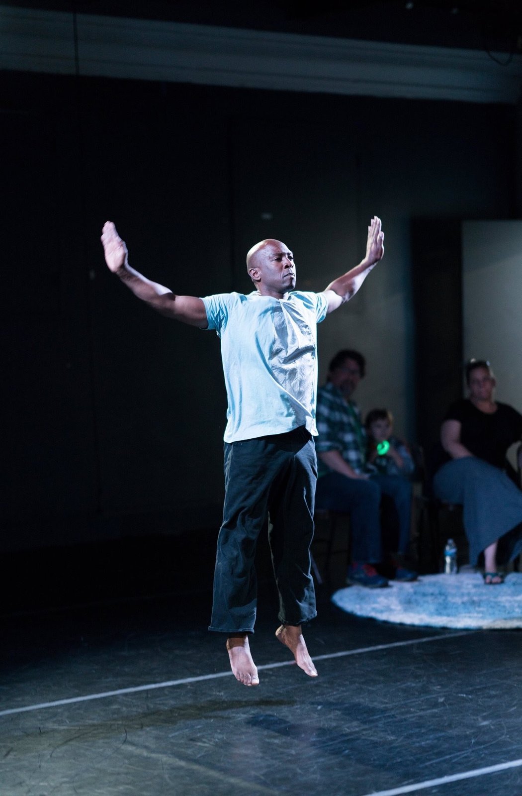 Boris Willis and a dancer reaching outward on a dim stage