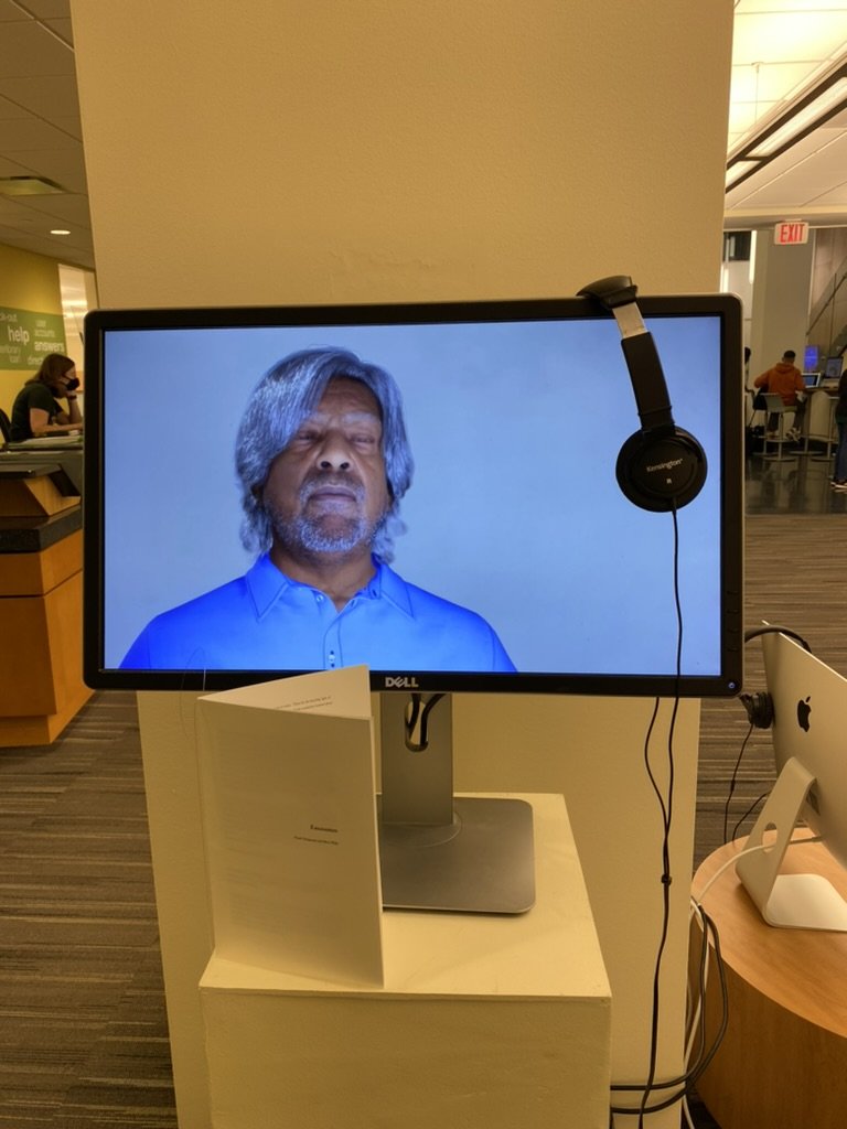 A MetaHuman of an older man with eyes closed, with headphones and a printed Encounters booklet on the pedestal