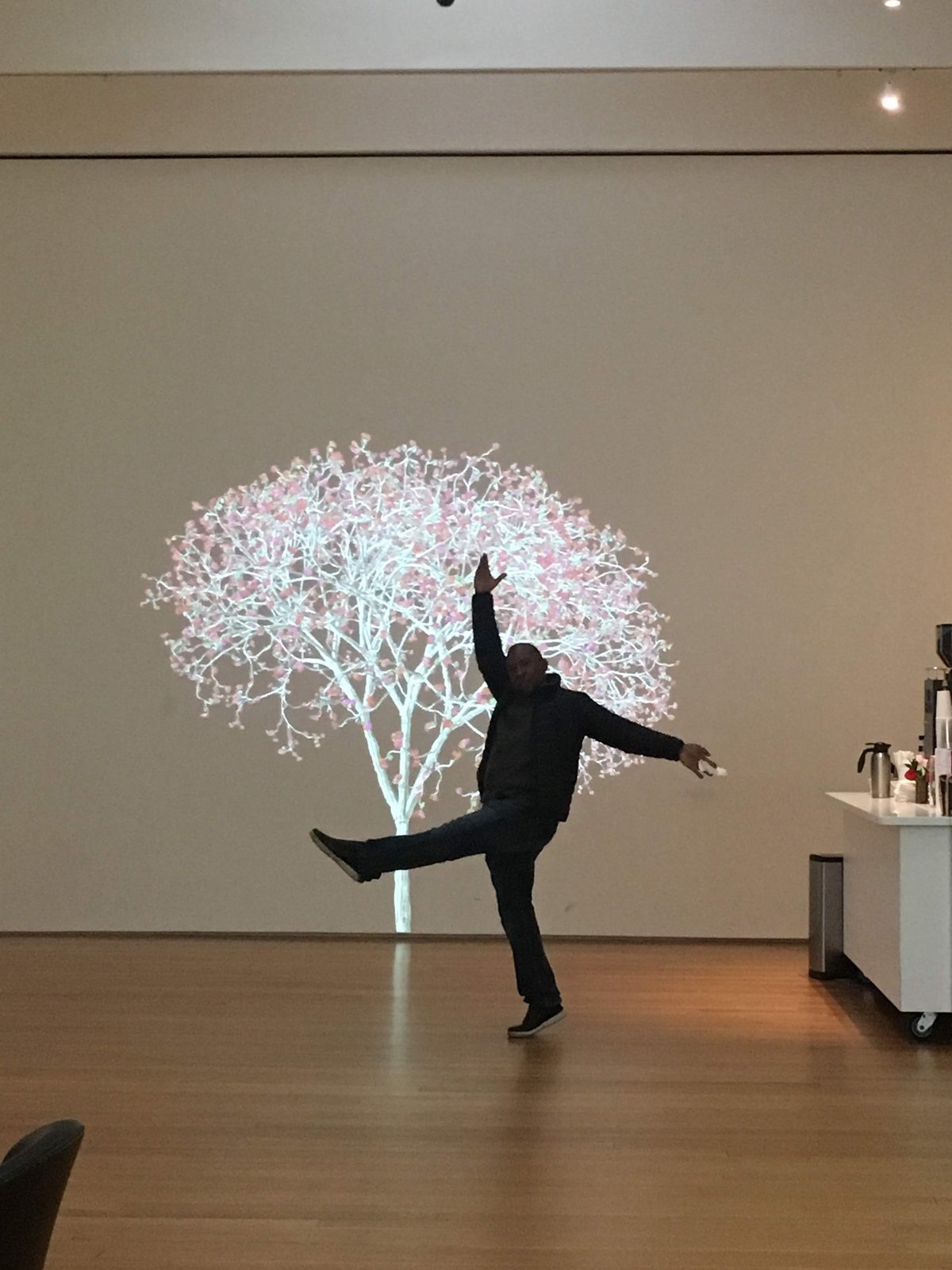 Boris Willis balancing on one leg before a glowing tree projection