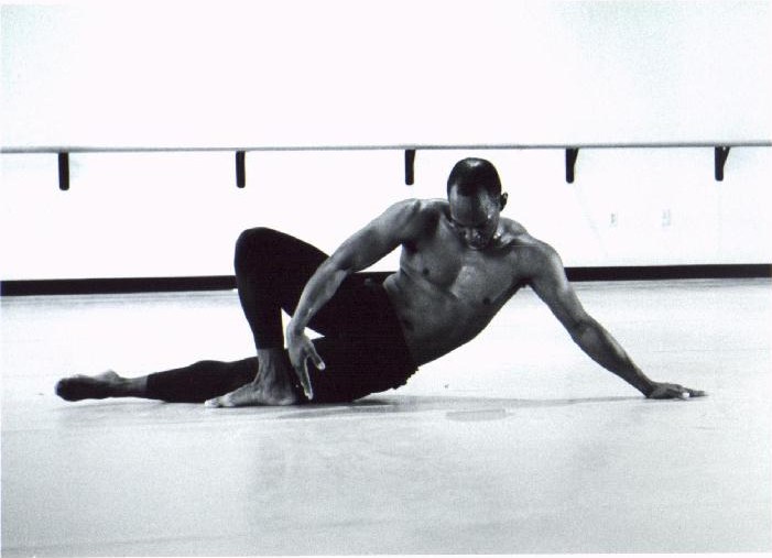 Black-and-white photograph of Boris Willis reclining on his side on the studio floor, propped on one arm