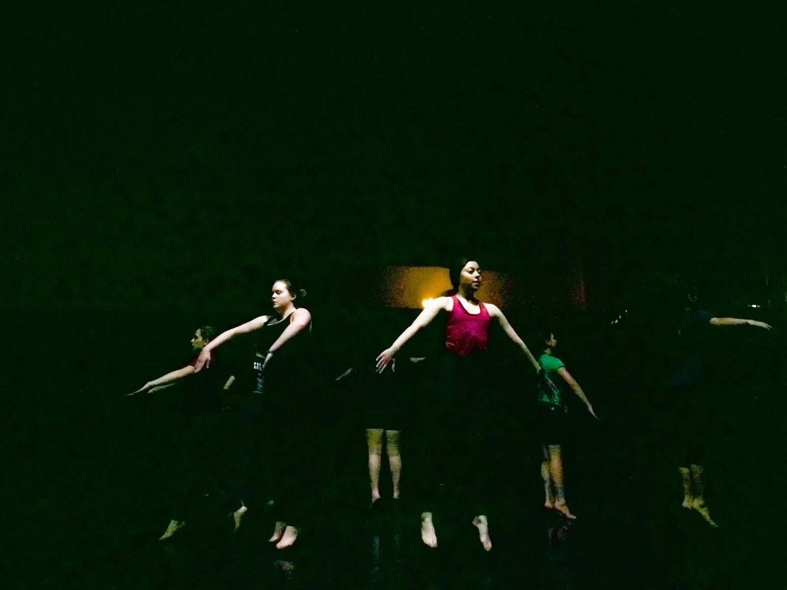 Dancers half-lit, shapes reading against a near-black stage