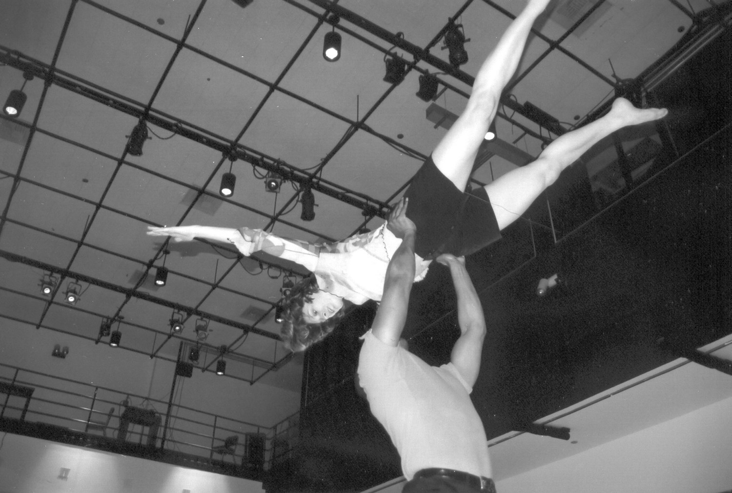 Emily Berry lifted overhead by Boris Willis beneath the theater lighting grid in Aliens