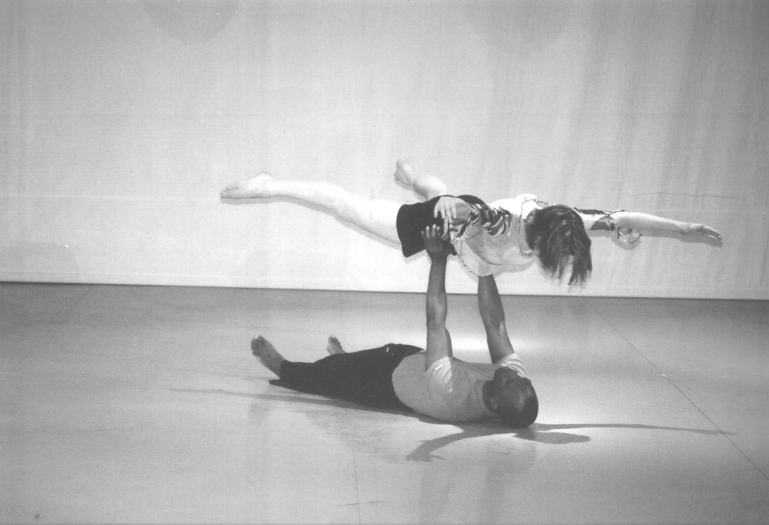 Boris Willis on the floor lifting Emily Berry overhead in a horizontal balance, Aliens