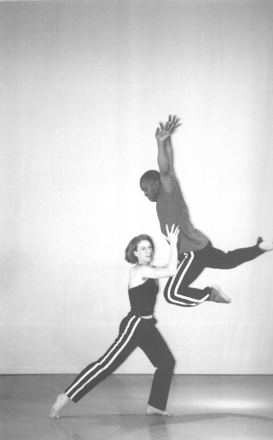 Boris Willis leaping beside Emily Berry in a deep lunge, both in striped track pants