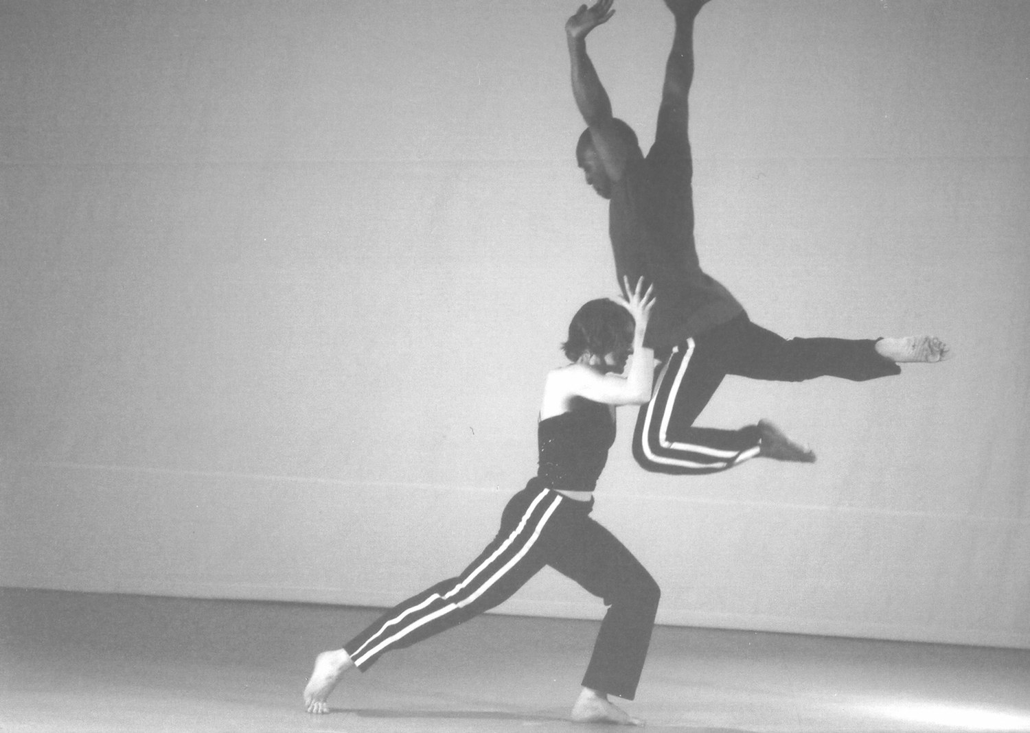 Boris Willis leaping past a dancer in a deep lunge