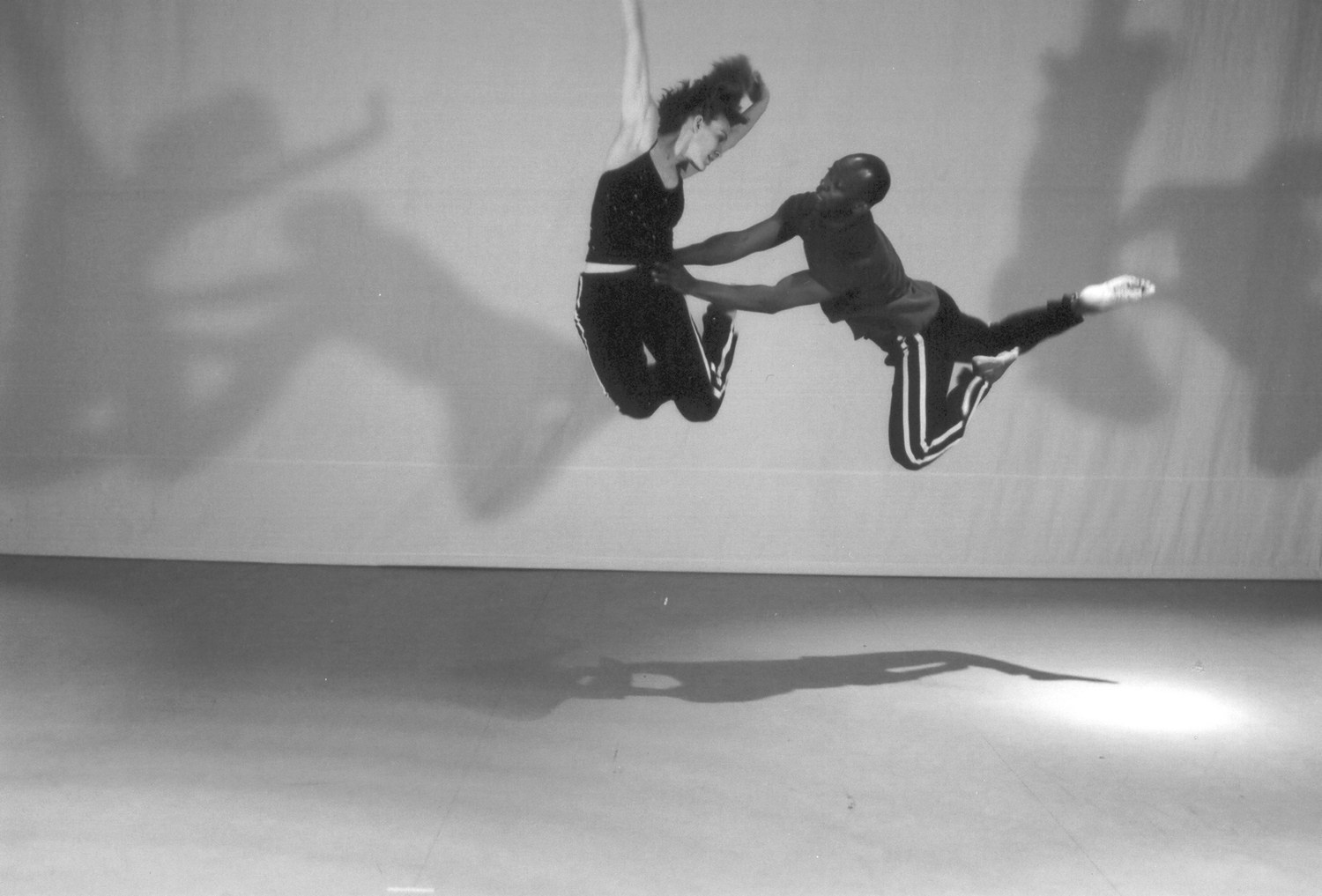 Two dancers airborne mid-leap against a studio backdrop